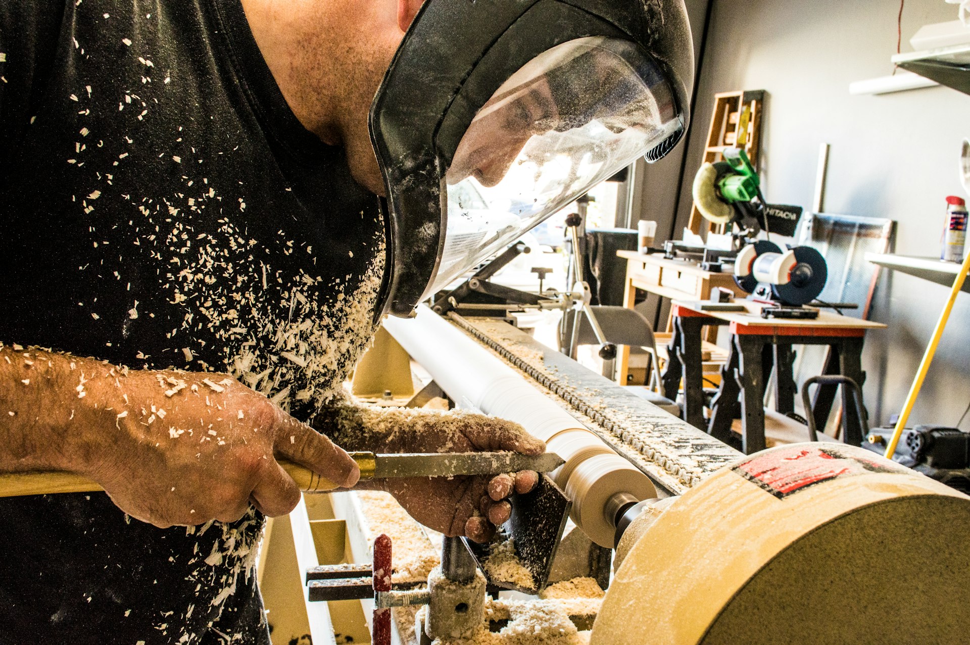wood worker man wearing welding helmet in front of industrial machine